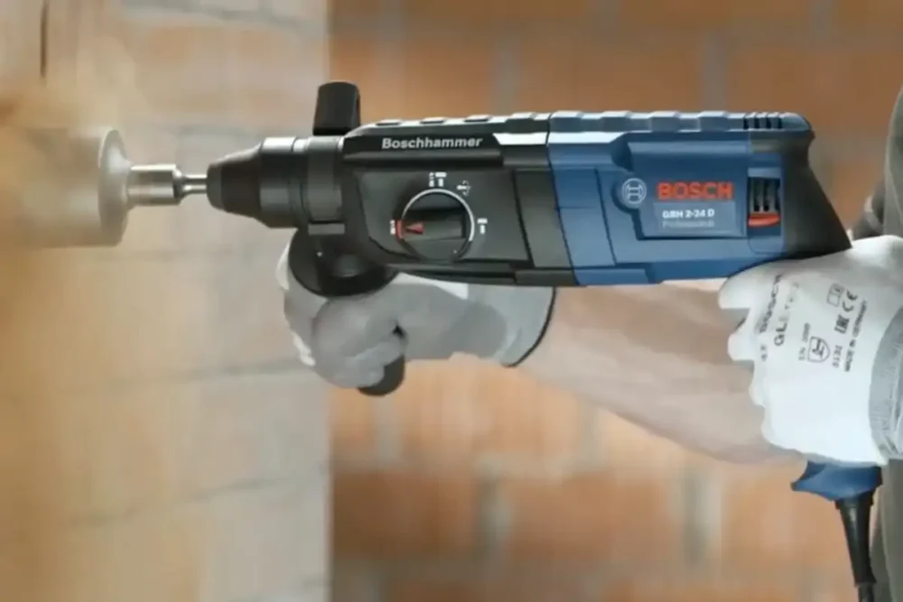 Martelete perfurador rompedor Bosch GBH 2-24D Professional com mandril SDS-Plus furando parede de tijolo, operador usando luva de proteção